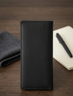 Black leather wallet on a wooden surface with a pen and notebook.